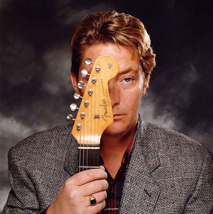 British singer-songwriter Chris Rea posing behind his guitar, late 1980s.